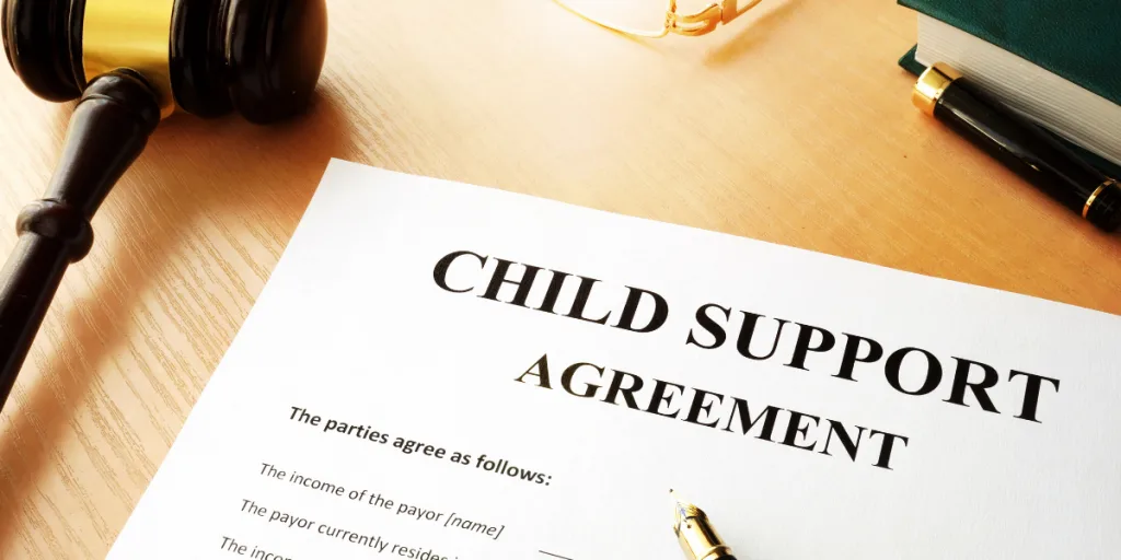 Child support agreement document on a desk with a gavel, pen and reading glasses