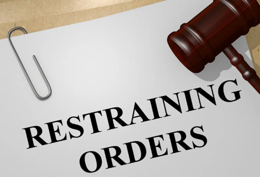 Document titled Restraining Orders on a folder beside a wooden gavel